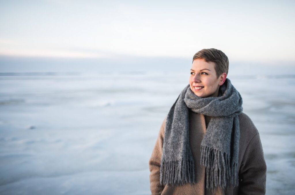 Jenni Pitko hymyilee ja katsoo maisemaan jäätyneellä merellä talvisessa seesteisessä maisemassa.