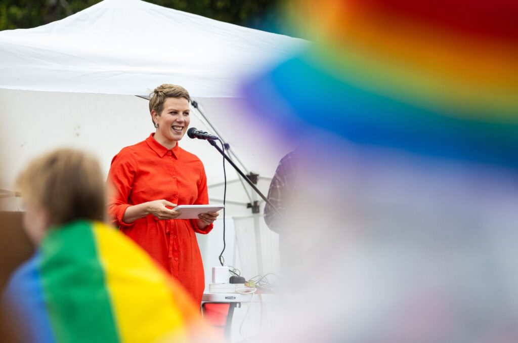 Vihreiden kansanedustaja Jenni Pitko pitää puhetta pride-tapahtumassa päällään kirkkaan punainen mekko.